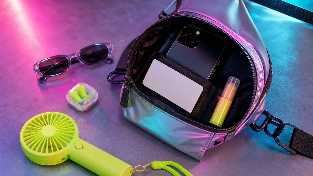 Festival bag essentials laid out with neon rave accessories